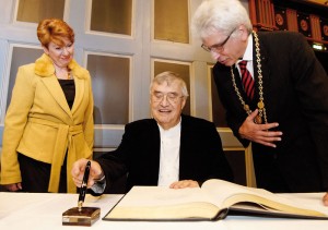 Zwischen Stadtverordnetenvorsteherin Petra Friedrich und Oberbürgermeister Bertram Hilgen trägt sich Peter Härtling ins Goldene Buch ein. Foto: Mario Zgoll